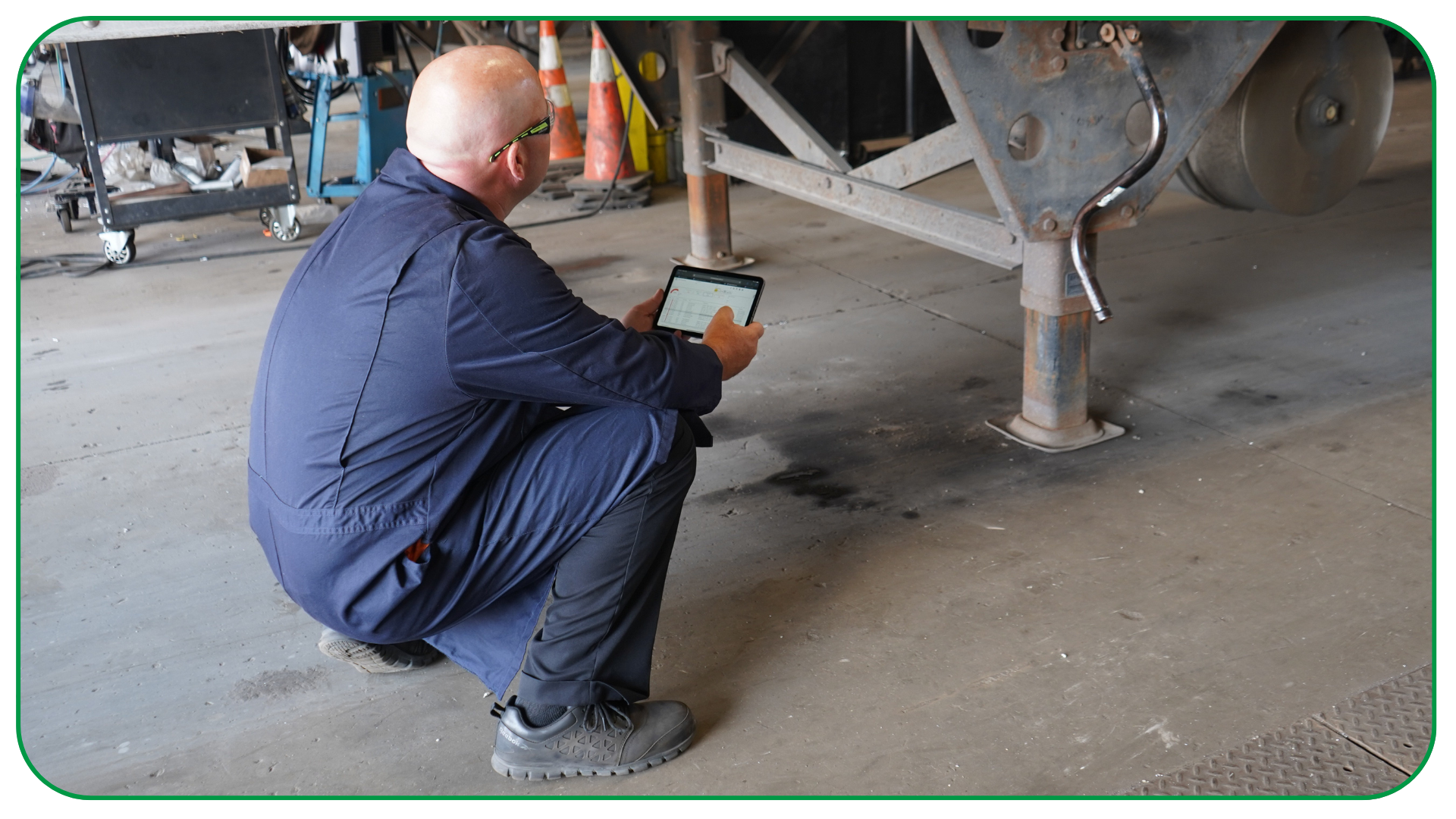 Technician checking under trailer for repair using ipad for fleet analytics